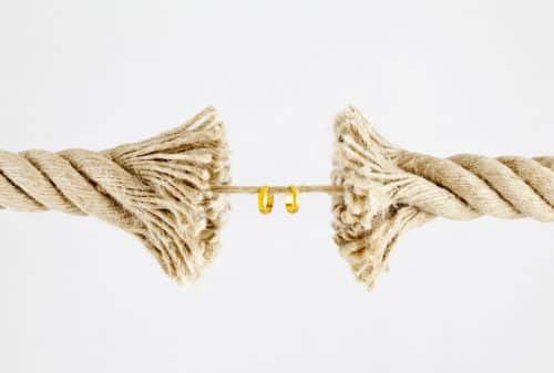 Wedding rings hanging on by a thread of a breaking rope