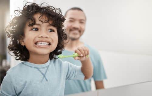 Shot of son and father brushing teeth, visual concept for a Utah family lawyer blog discussing Utah Child Support Guidelines.