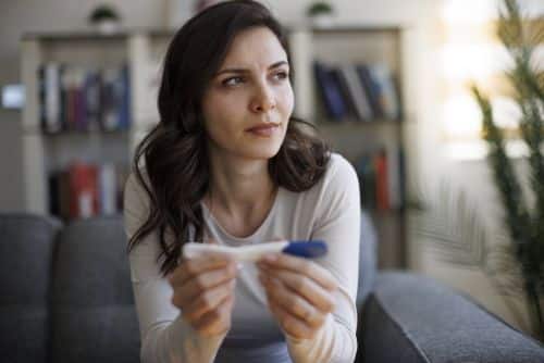 Thoughtful young woman holding a pregnancy test visual concept for a family law blog discussing prenatal child support.