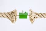 A fraying tug-of-war rope pulling on a house with US Dollar bills. - Ashley Wood Law, P.C.