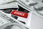 Looking down on a magnifying glass “Divorce” computer button and dollar bills concept for discovery in divorce.