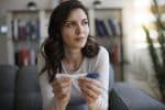 Thoughtful young woman holding a pregnancy test visual concept for a family law blog discussing prenatal child support.